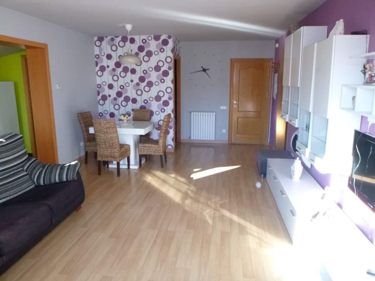 Sala d’estar amb sofà, parets liles i parquet